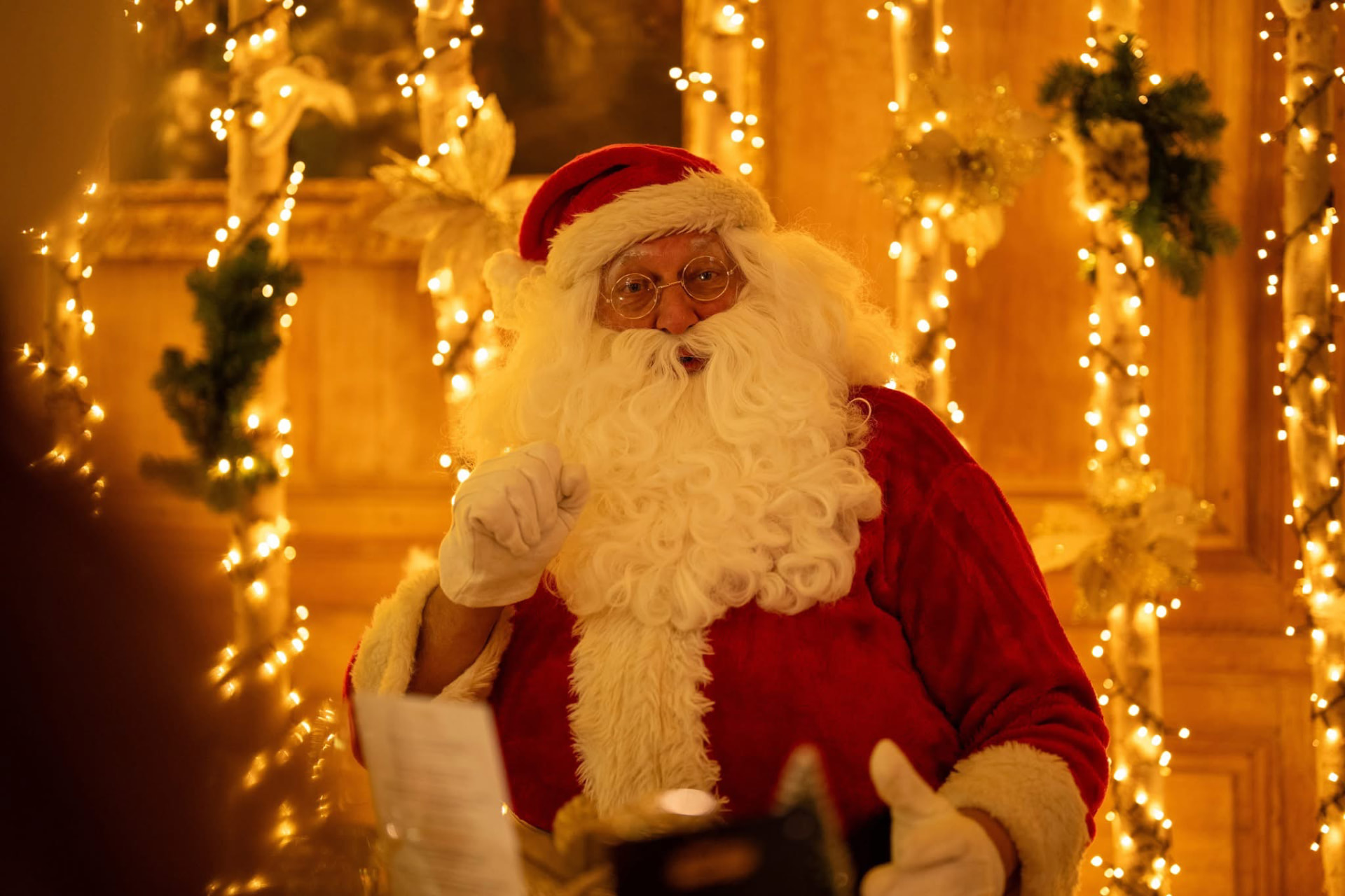 LE PÈRE NOËL souriant entouré de guirlandes lumineuses